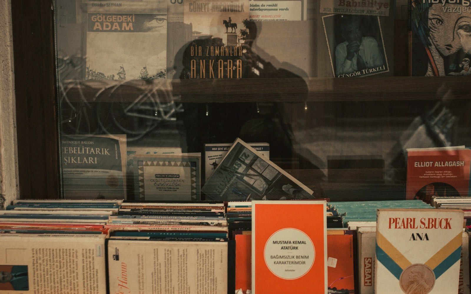 A bookshop window display with spines in Spanish and Portuguese, reflections in the glass