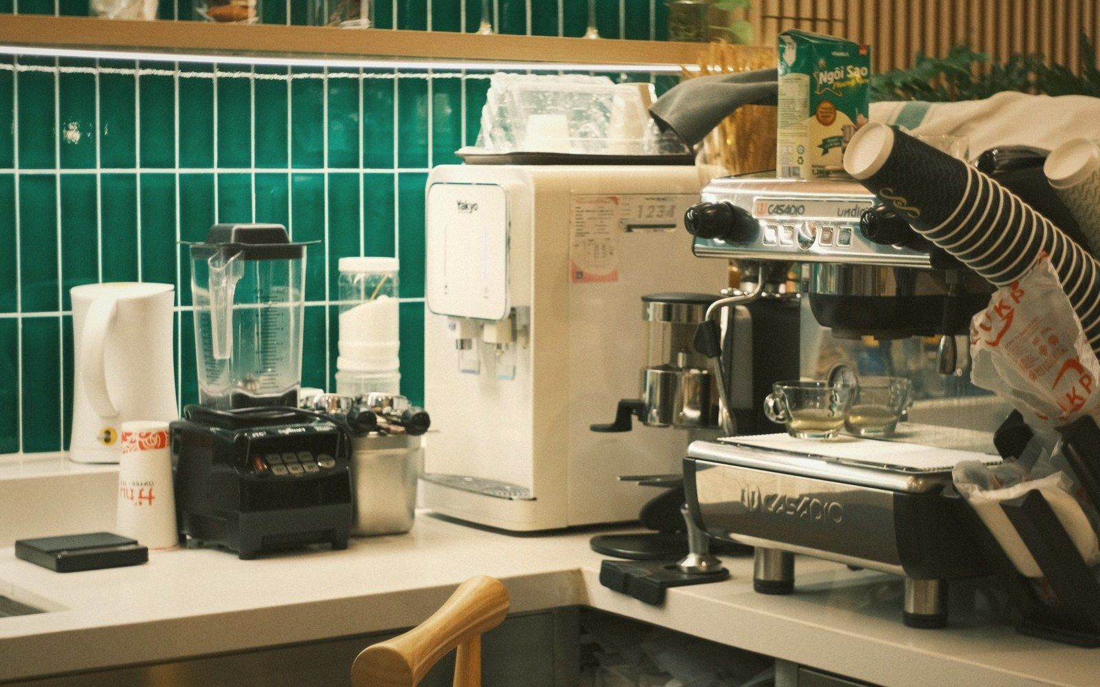An espresso and a small bread roll on a tiled café counter, surface worn