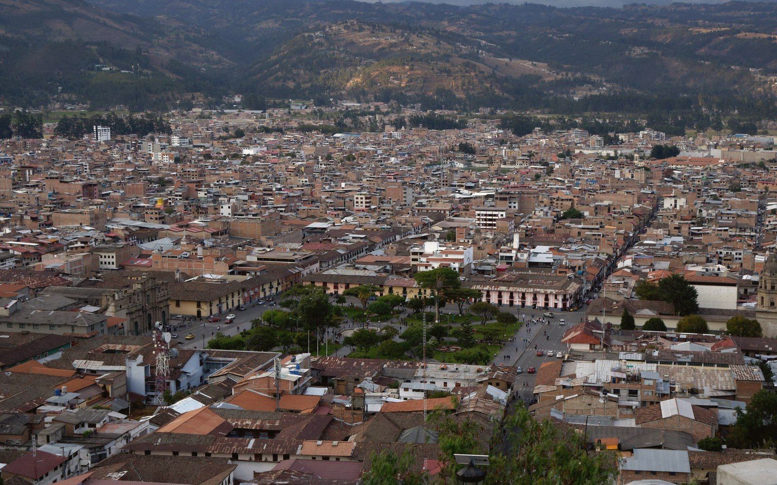 Aerial view of a dense city grid with a central plaza, surrounded by hills