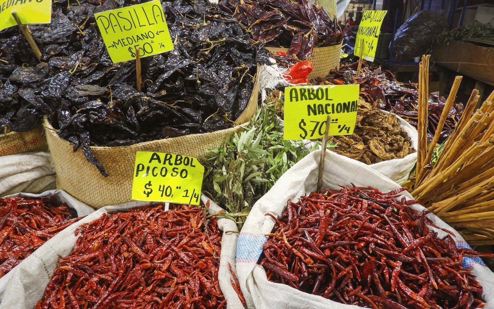 Sacks of dried chilli peppers with handwritten price signs at a market stall