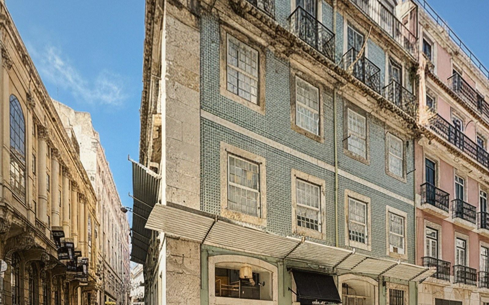 Blue azulejo tiles cover the facade of a narrow multi-story building with iron balconies
