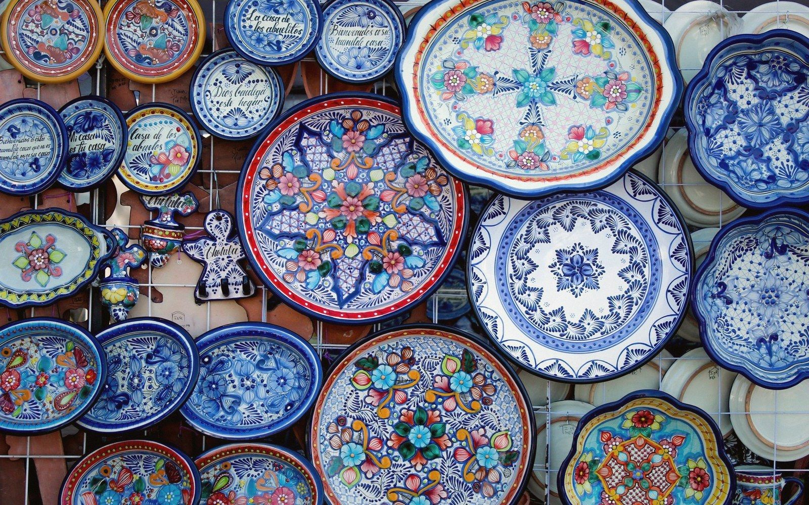 Hand-painted ceramic plates and platters with floral patterns displayed on a wall